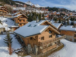 A wooden chalet with a balcony, surrounded by snow-covered houses and mountains. - Chalet Bacaro - 12 guests (Les Allues)