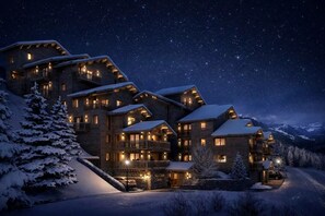 Ein mehrstöckiges Holzhaus mit Balkonen, schneebedeckten Dächern und einem sternenübersäten Nachthimmel.