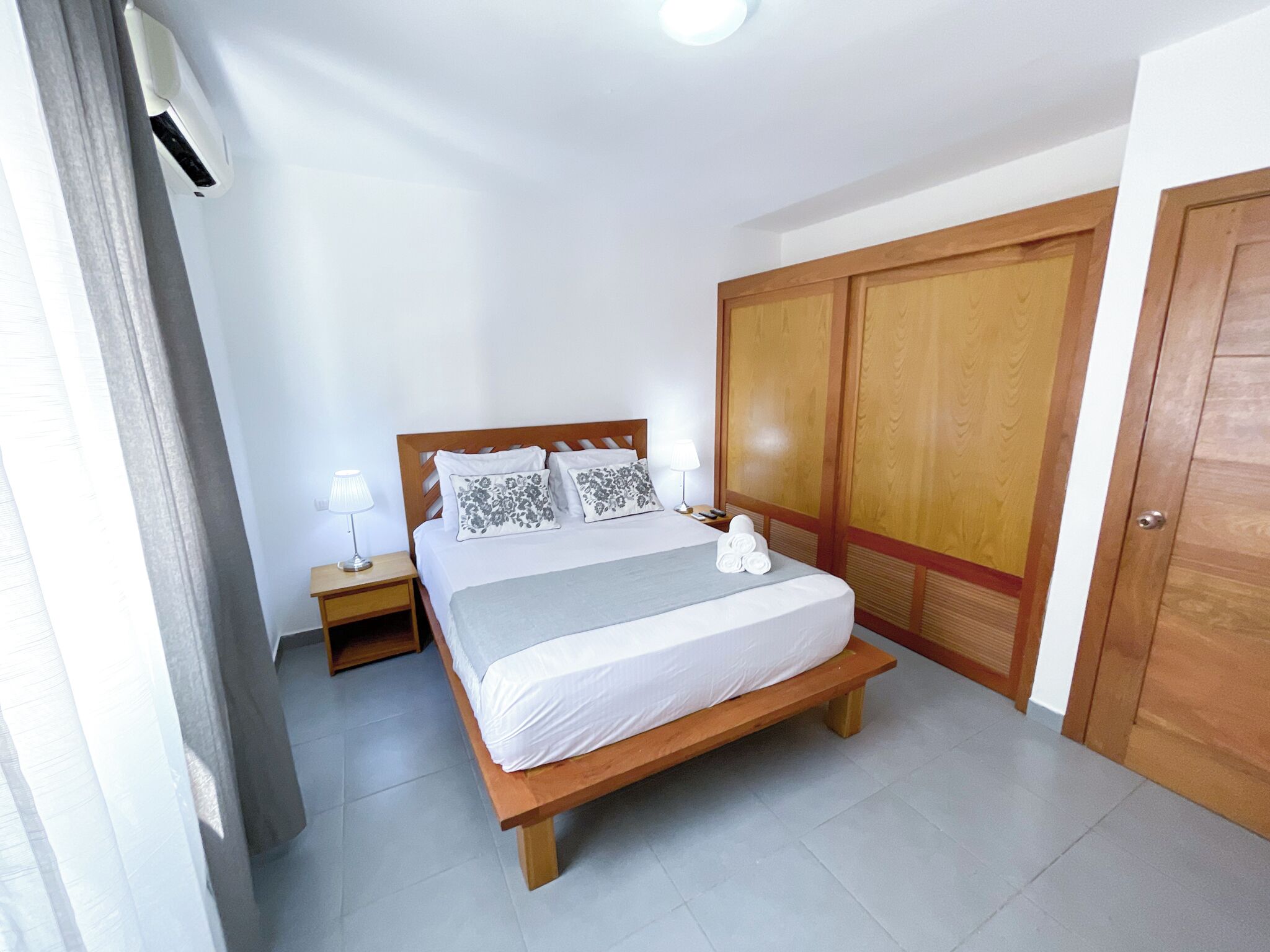A bedroom with a bed, bedside tables, a wardrobe, and a curtain.