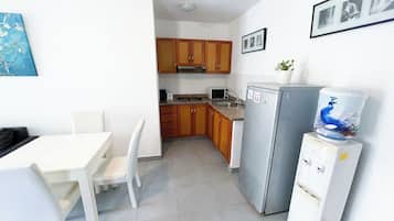 A compact kitchen with wooden cabinets, a white refrigerator, and a dining area with a white table and chairs.