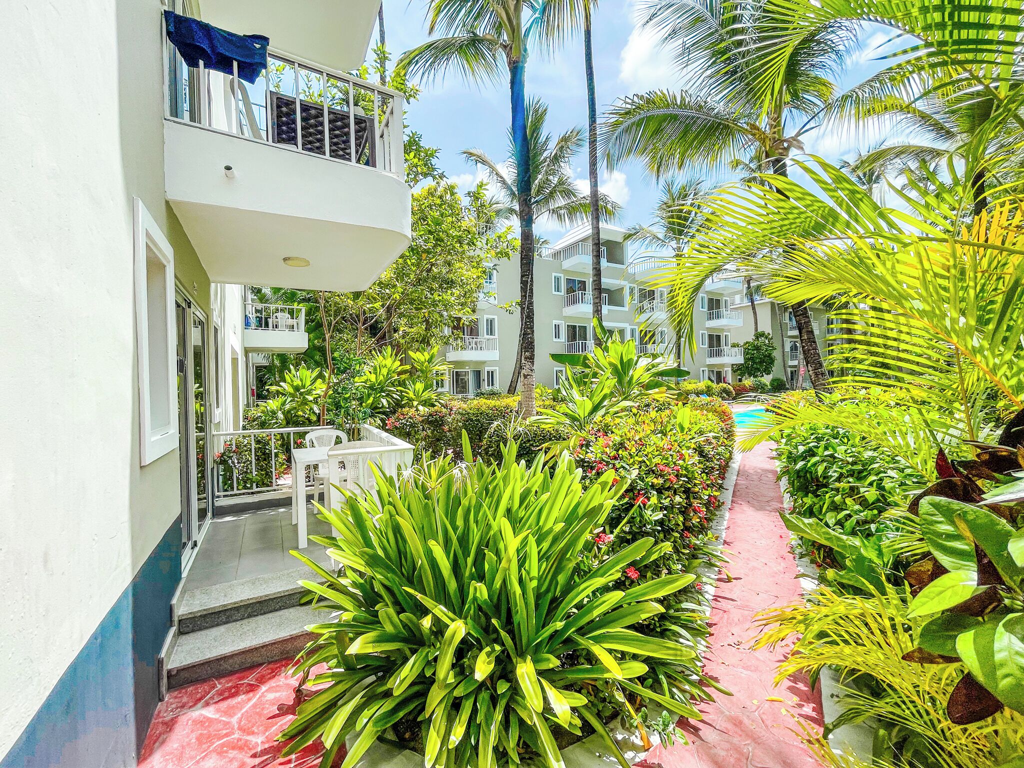 A hotel courtyard with a pool, surrounded by lush greenery and palm trees.