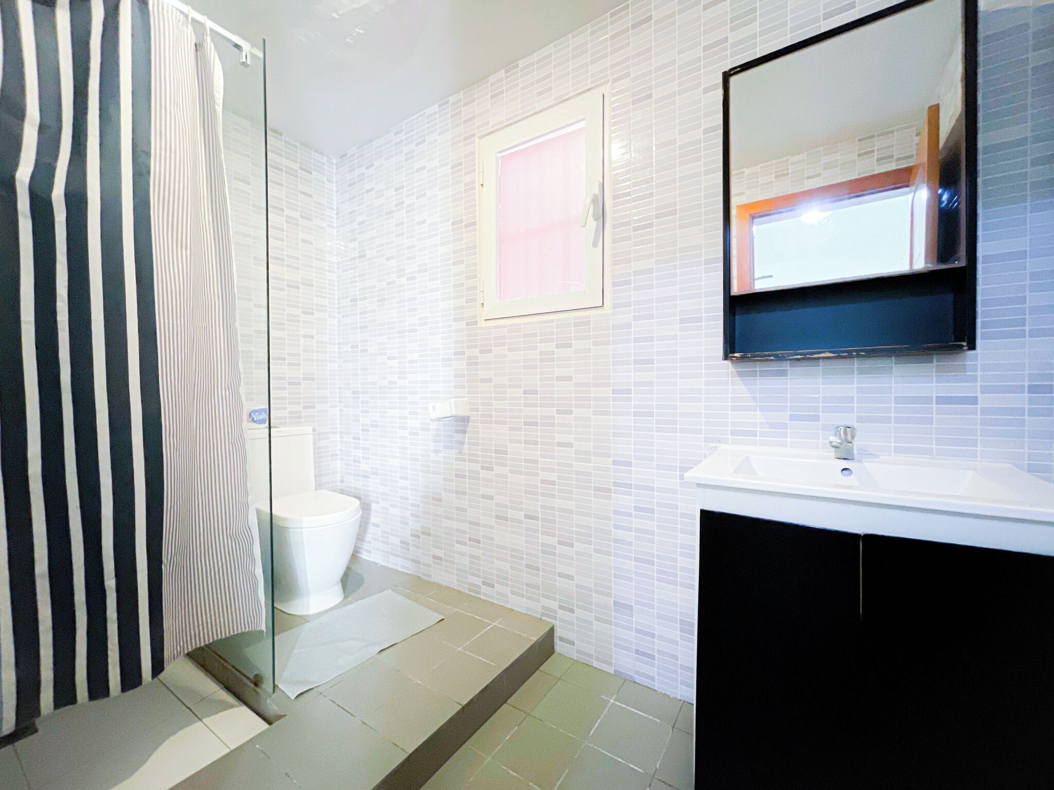 Un bagno con doccia, servizi igienici, lavandino e specchio.