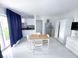 Una cocina moderna con armarios blancos, una mesa de comedor de madera y un refrigerador.