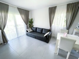Una sala moderna con un sofá gris, una silla blanca y una mesita.