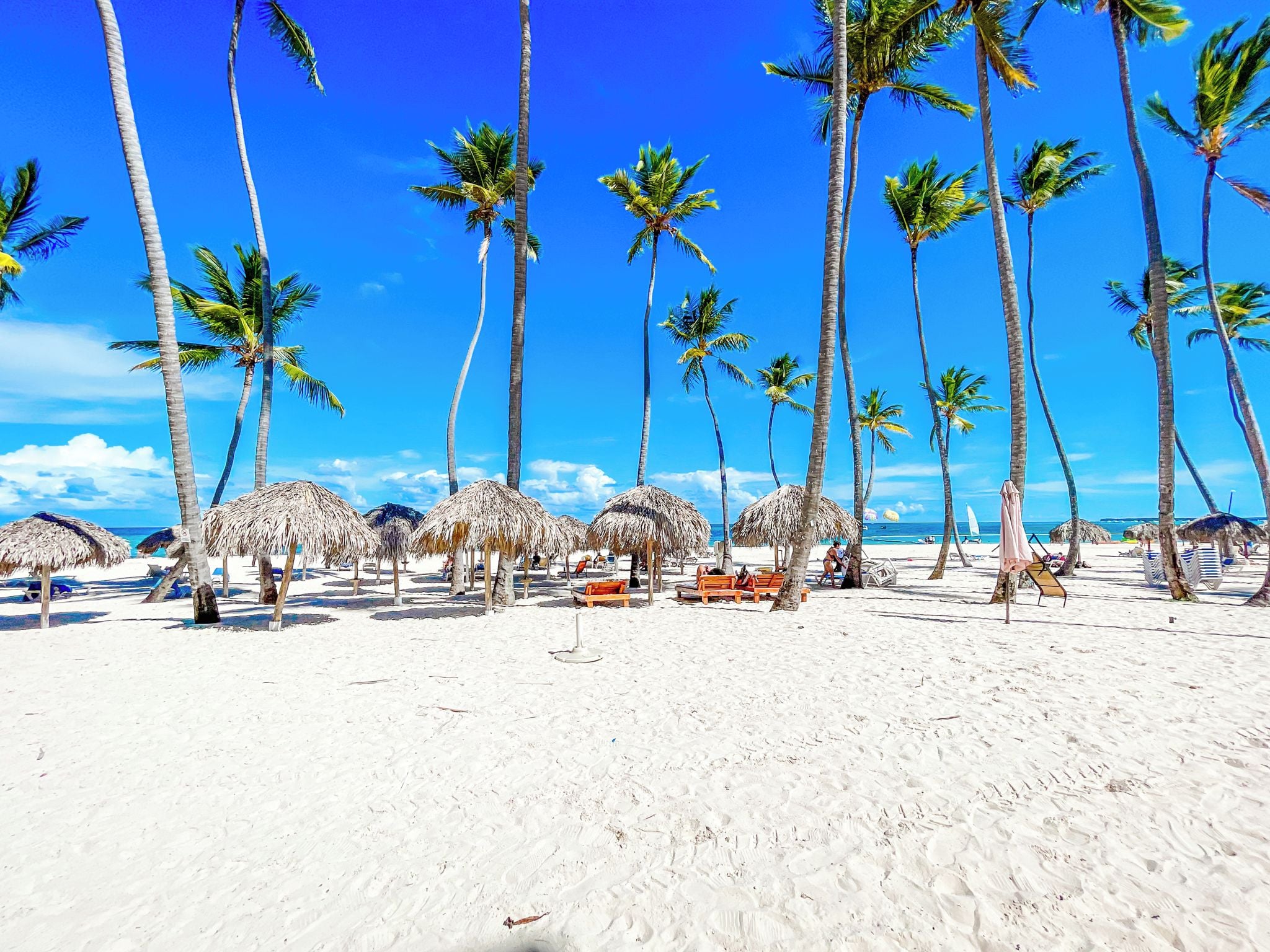 Aan het strand, wit zand, ligstoelen aan het strand, parasols