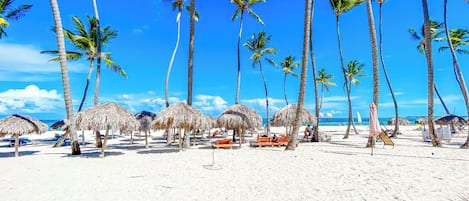 En la playa, playa de arena blanca, camastros y sombrillas
