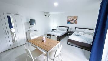Ein Hotelzimmer mit zwei Betten, einem Schreibtisch, einem Stuhl, einem Fernseher und einem Bild an der Wand.
