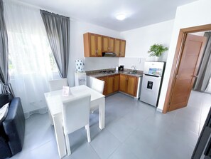 Una cocina compacta con armarios de madera, una mesa blanca y un refrigerador.