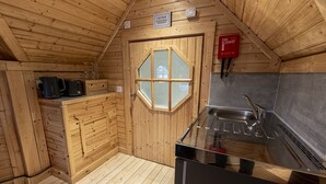 A compact kitchen with a wooden interior, a window, a sink, and a fire blanket sign.