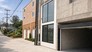 Un edificio moderno con garaje, fachada de concreto y entrada pavimentada.