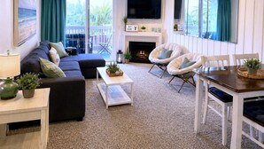 Un salon comprenant un canapé, des fauteuils, une table basse, une cheminée et un téléviseur.