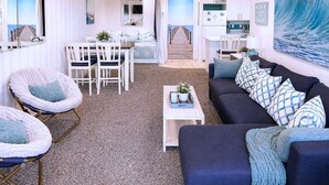 Un salon moderne avec vue sur la mer, un coin repas et une cuisine.