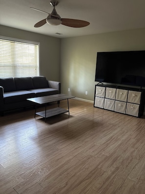 A living room with a sofa, a coffee table, a TV, and a ceiling fan. - Serene 4-bedroom house with AC in charming Columbia (Columbia)