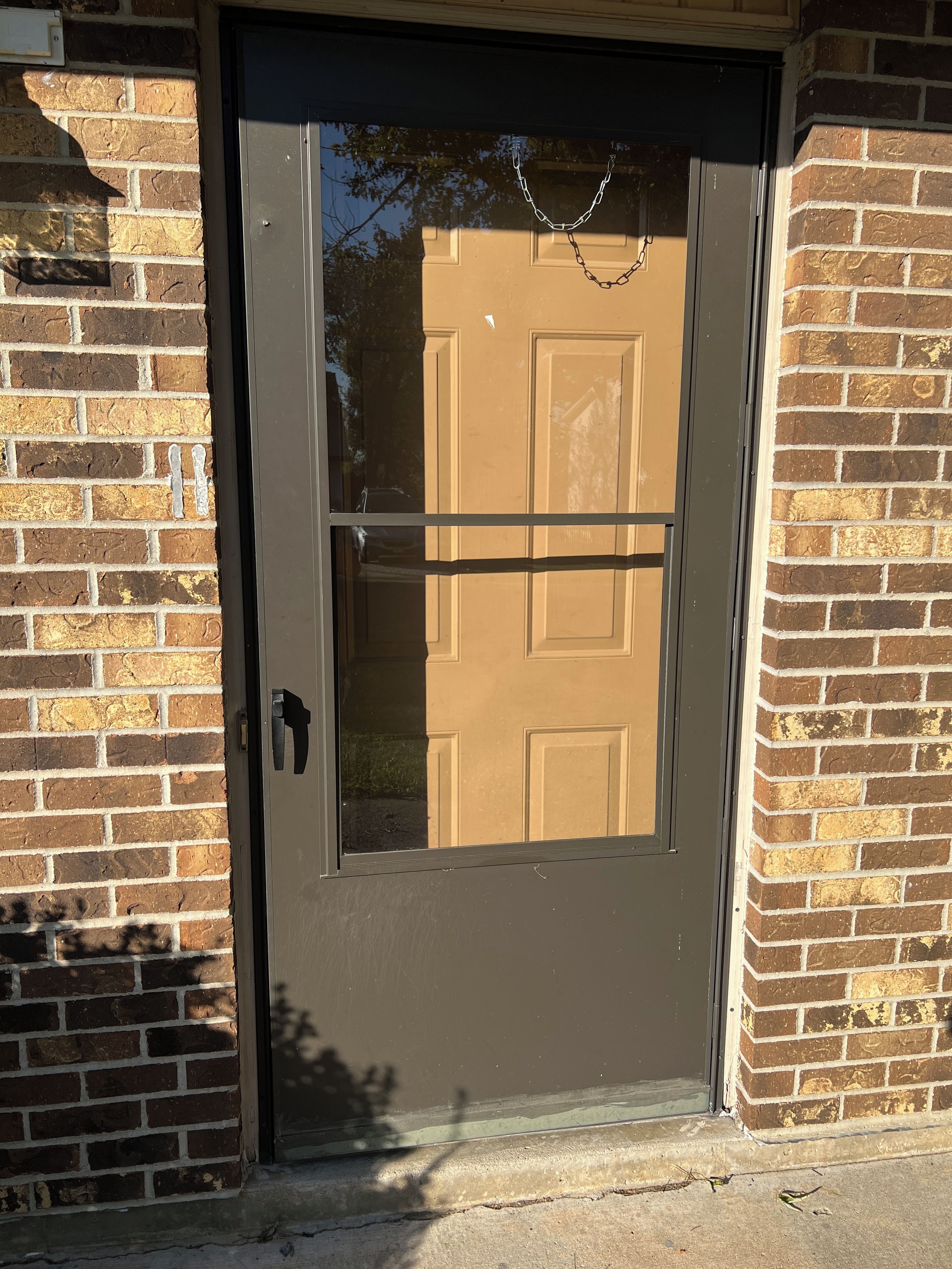 A door with a chain lock, a metal handle, and a glass panel.