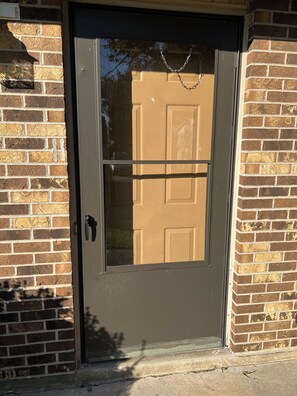 A door with a chain lock, a metal handle, and a glass panel.