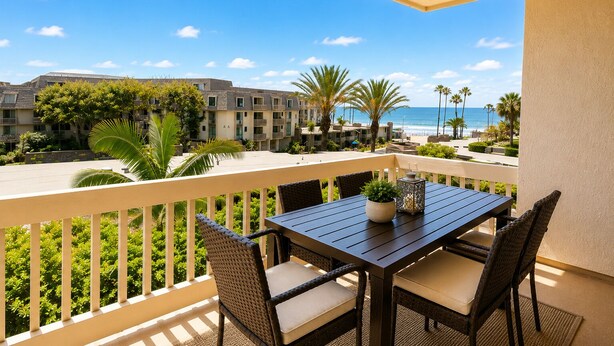 A balcony with a table and chairs, overlooking a beach and hotel buildings. - SolMar Vista 2BR/2BA Oceanview, Heated Pools, Hot Tubs & Steps to Beach (Oceanside)