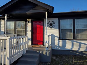 Ein Haus mit roter Tür, weißen Geländern und einem Sternemblem an der Wand.