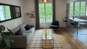 Een moderne woonkamer met een bank, salontafel, eettafel, stoelen en een groot raam met uitzicht.