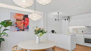 Une cuisine moderne avec des meubles blancs, un îlot central et des luminaires suspendus.