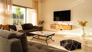Ein modernes Wohnzimmer mit einer Couch, einem Couchtisch und einem an der Wand befestigten Flachbildfernseher.
