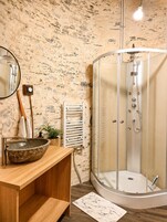 Um banheiro com lavatório de pedra, porta-toalhas, aquecedor e chuveiro com cabine de vidro.