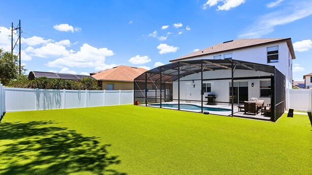 Uma casa com área externa coberta, piscina e gramado.