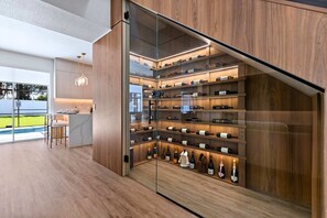 A modern kitchen with a wine rack, bar area, and large windows. - Upstay Contemporary Retreat w Pool, BBQ & Backyard (Davenport)