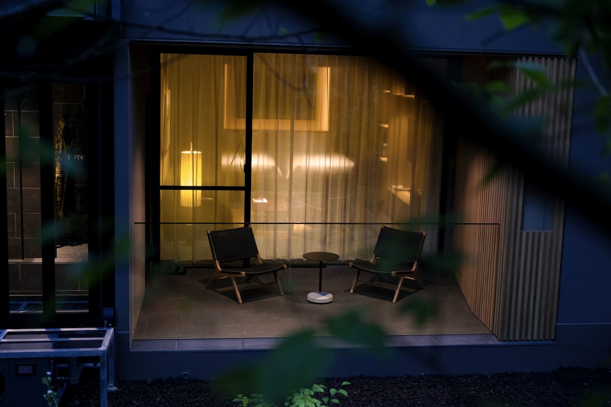 A modern building with large windows, two chairs, and a small table outside.