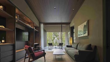 A modern interior with a sofa, chairs, a coffee table, and a kitchen area.