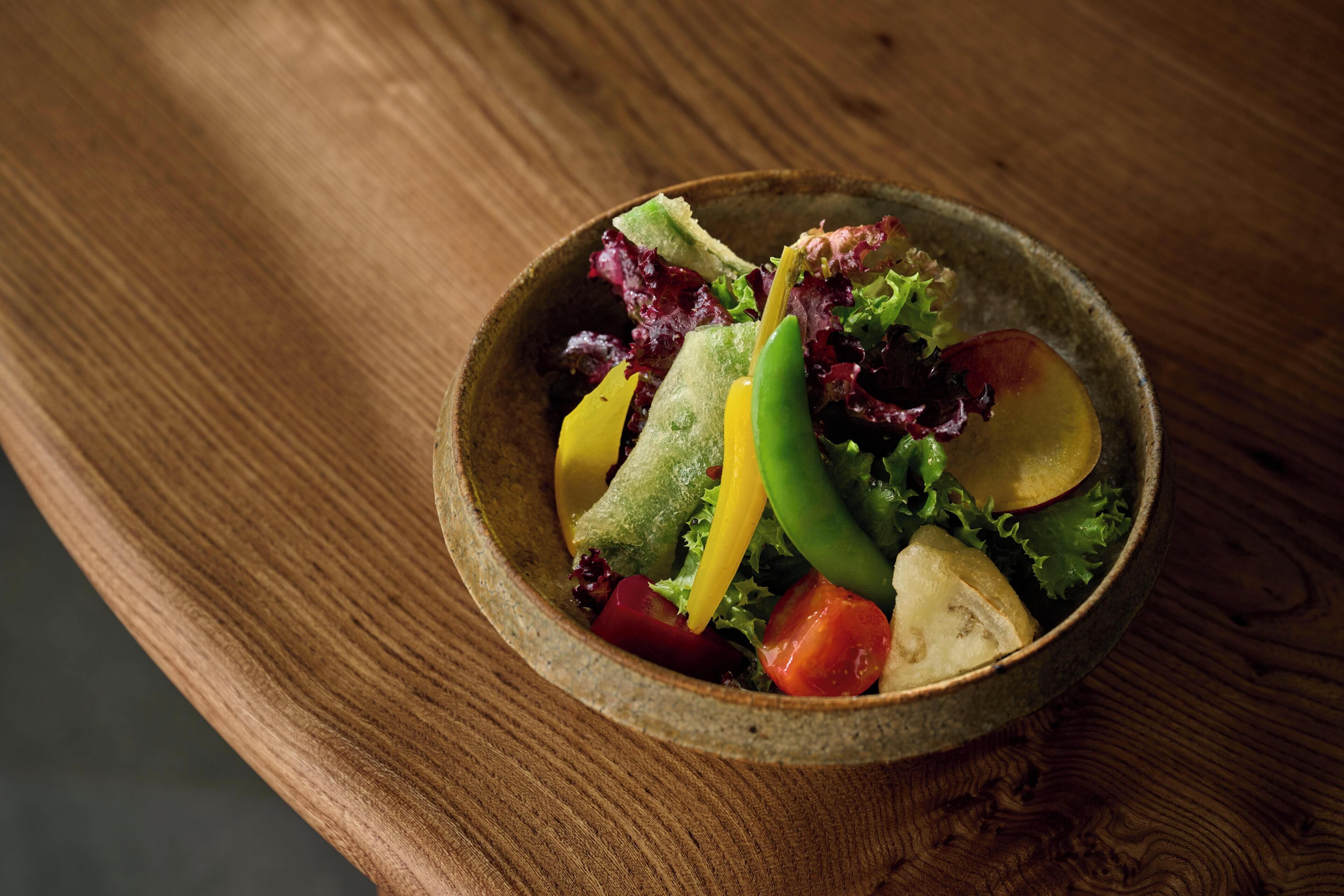 Un saladier rempli de salade sur une table en bois.