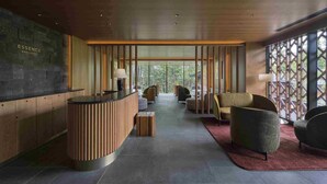 A reception area with a wooden reception desk, seating, and a view through a lattice window.