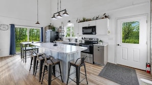 A modern kitchen with a large island, bar stools, a microwave, and a sink. - Peaceful Cobalt Cottage on the Bay in Oconto (Oconto)