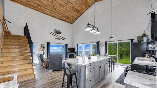 A spacious kitchen with a large island, wooden staircase, and a view of the outdoors. - Peaceful Cobalt Cottage on the Bay in Oconto (Oconto)