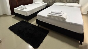 A modern bedroom with two single beds, a large marble headboard, a dark wooden wardrobe, and a black rug.