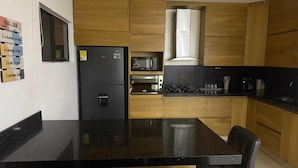 A modern kitchen with wooden cabinets, a black countertop, and a built-in microwave.