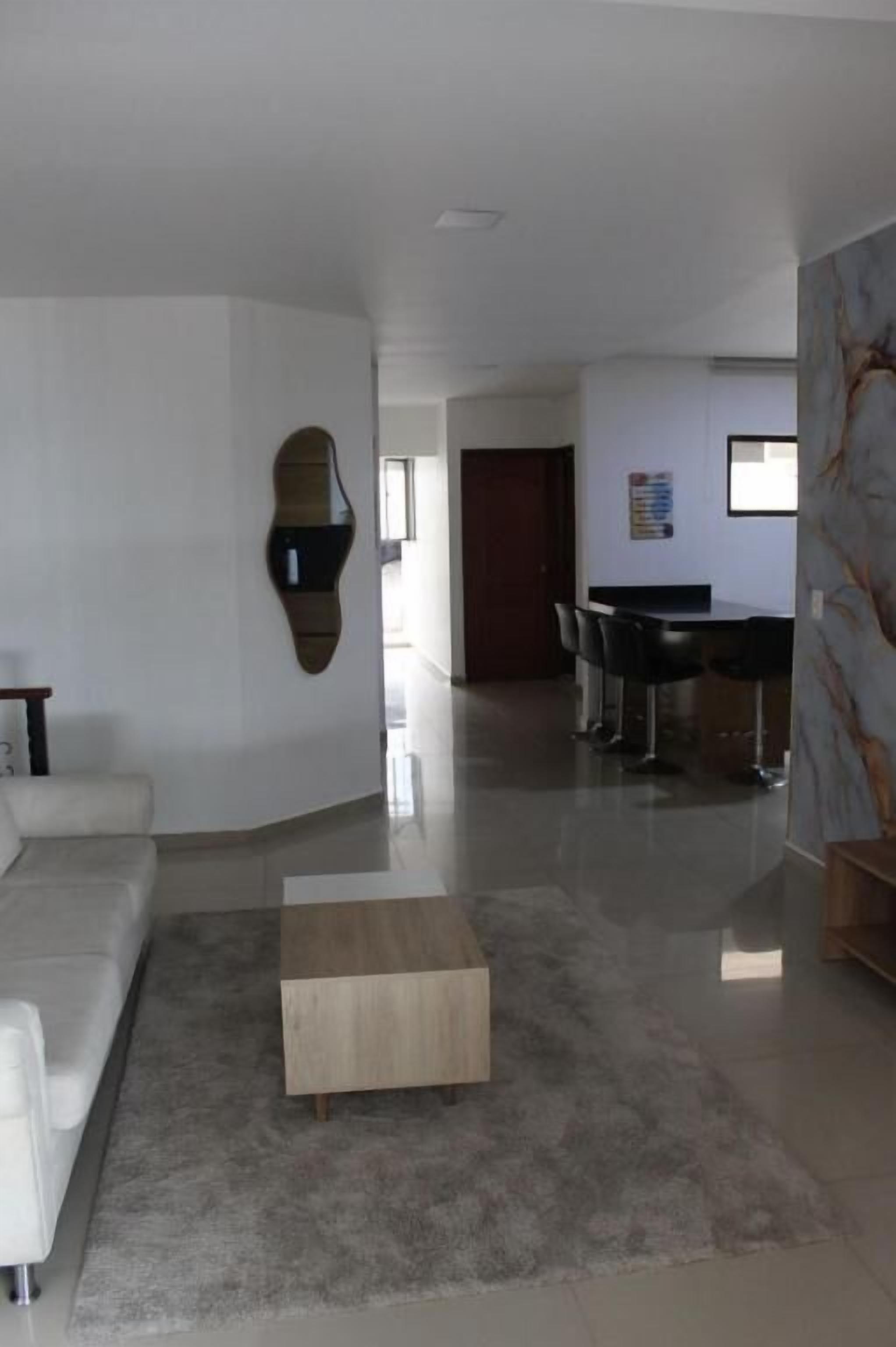A modern living room with a sofa, a coffee table, and a dining area with chairs.