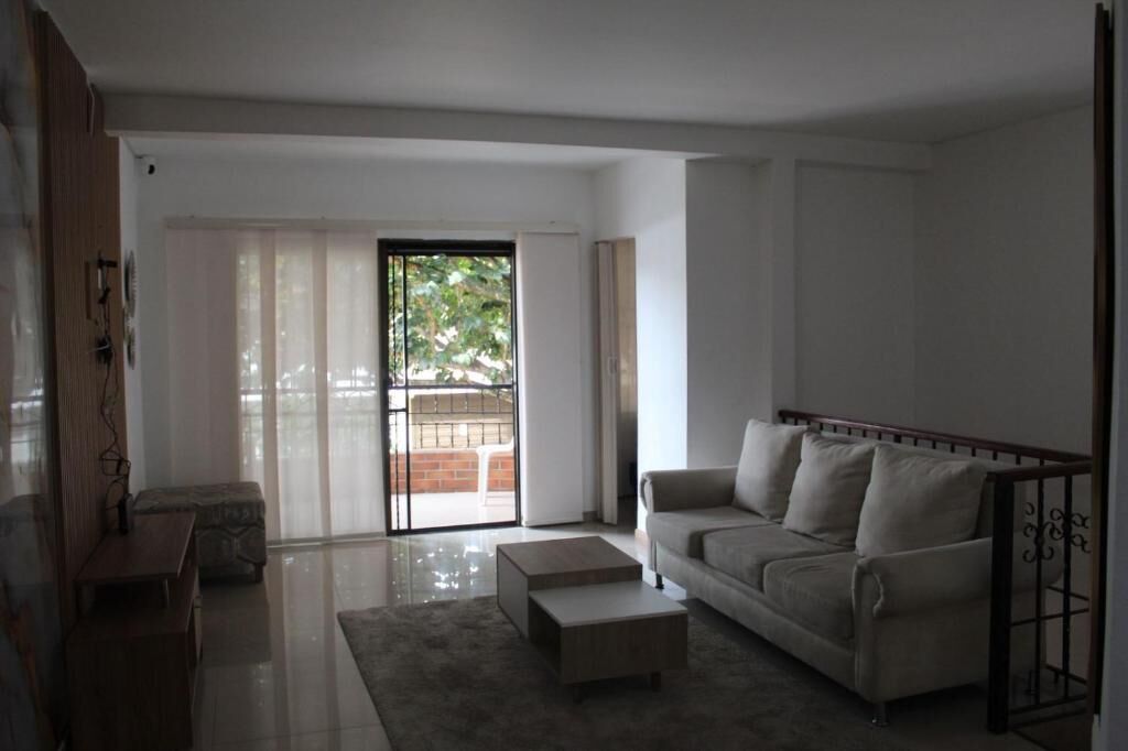 A spacious living room with a sofa, coffee table, and a sliding glass door leading to an outdoor area.