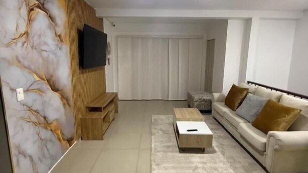 A modern living room with a flat-screen TV, a sofa, a coffee table, and a decorative wall.