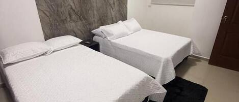 Una camera da letto con due letti, un tappeto scuro e una parete in marmo.