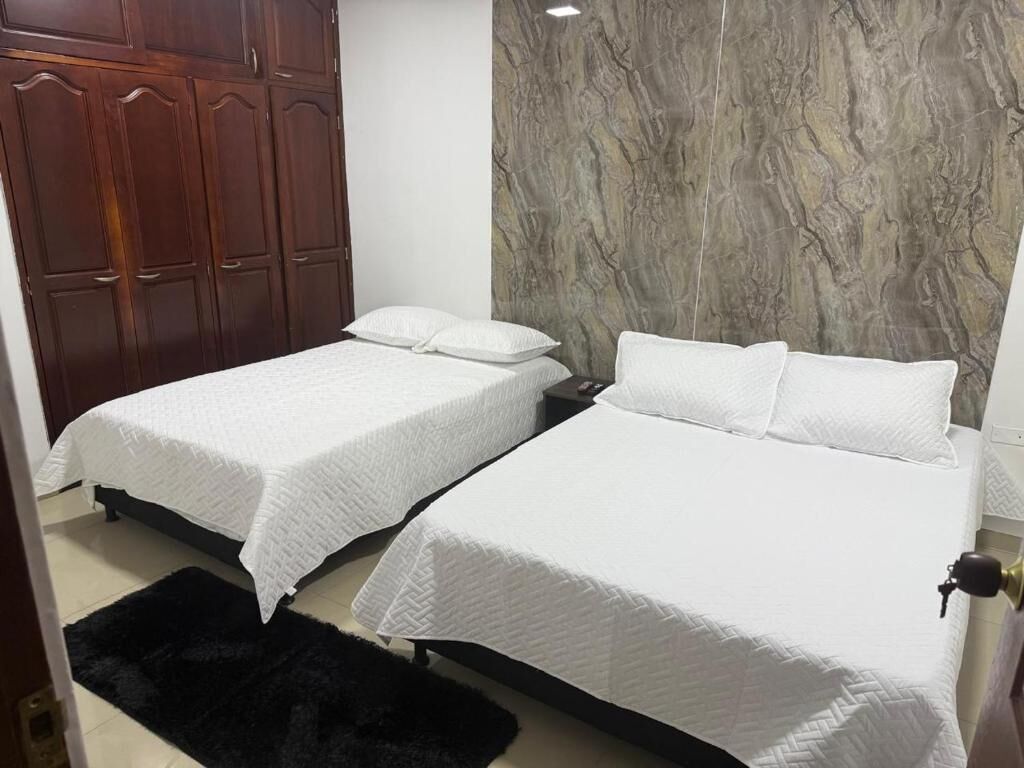 Un dormitorio con dos camas, un armario y una pared de mármol.
