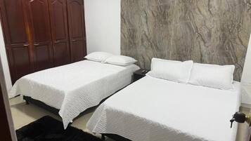 Un dormitorio con dos camas, un armario y una pared de mármol.