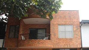 A two-story brick house with a balcony, a garage, and a window with blinds.