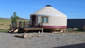 Une yourte dotée d’une terrasse en bois et d’une seule fenêtre.