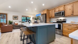 A modern kitchen with wooden cabinets, stainless steel appliances, and a large island. - Twisted Cedar Retreat - River views w/Firepit! (Ingram)