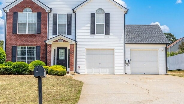 A two-story house with a garage, a mailbox, and a well-maintained lawn. - Spacious Corner-Lot Sanctuary w/ Sunroom and Deck in Ellenwood, Georgia (Ellenwood)