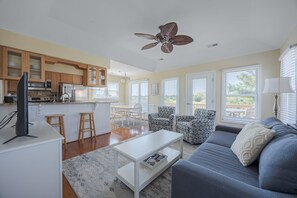 A modern living space with a kitchen, dining area, and seating area. - 5600 - On the Sunny Side Soundside 3BR retreat with deck, Wi-Fi, and golf views. (Nags Head)