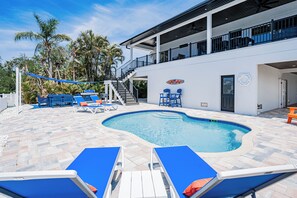 Ein Schwimmbad mit Liegestühlen, einem Grill und einer Treppe, die zu einem Balkon führt.