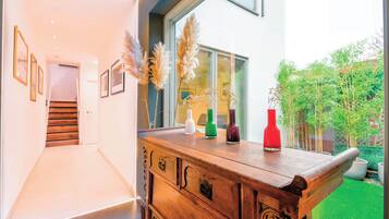 A modern interior with a wooden bench, framed pictures on the wall, and a view of the outside.