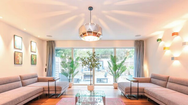 Ein modernes Wohnzimmer mit einem Glastisch, zwei Sofas, einem großen Fenster und einer Hängelampe.