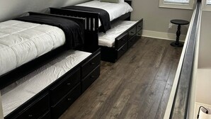 A bedroom with two beds, a small table, and a window. - Charming  Rustic cabin w/Jacuzzi at Fowler Lake, SK (Loon Lake No. 561)